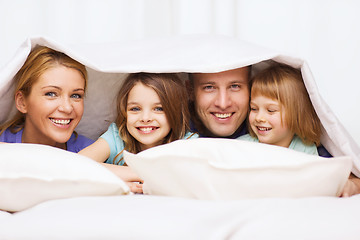 Image showing happy family with two kids under blanket at home