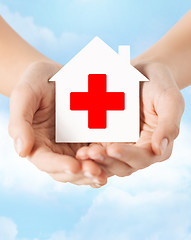 Image showing hands holding paper house with red cross