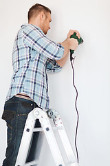 Image showing man with electric drill making hole in wall