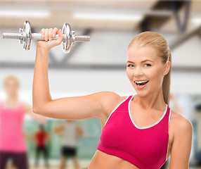 Image showing smiling woman with heavy steel dumbbell