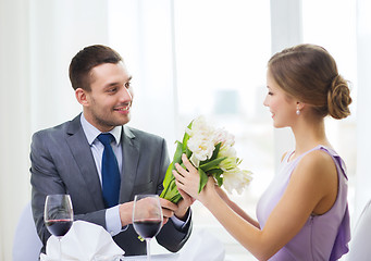 Image showing smiling man giving flower bouquet at restaurant