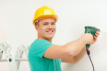 Image showing man with electric drill making hole in wall