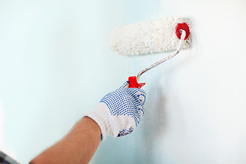 Image showing close up of male in gloves painting wall