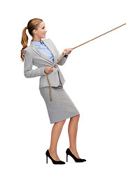 Image showing smiling businesswoman pulling rope