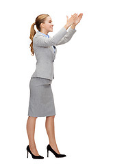 Image showing smiling businesswoman holding something imaginary