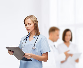 Image showing smiling female doctor or nurse with clipboard