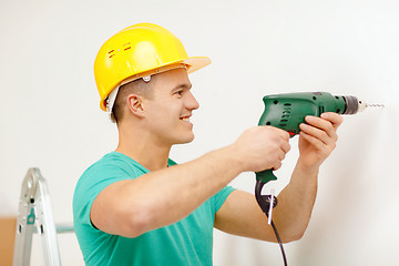 Image showing man with electric drill making hole in wall