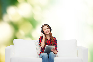 Image showing girl sitting on sofa with headphones and tablet pc