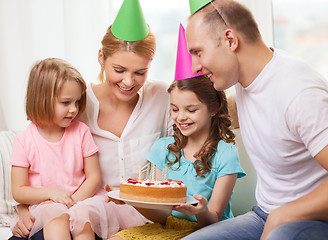 Image showing smiling family with two kids in hats with cake