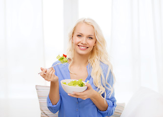 Image showing smiling young woman with green salad at home