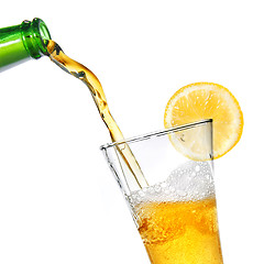 Image showing Beer pouring from bottle into glass with lemon isolated on white