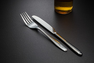 Image showing bottle of beer, knife and fork on black