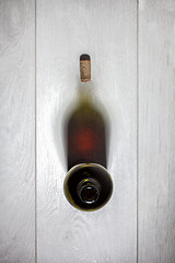 Image showing Bottle of red wine with cork on white wooden table. Top view