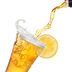 Image showing Beer pouring from bottle into glass with lemon isolated on white