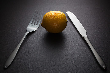 Image showing lemon with knife and fork on black
