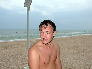 Image showing a wet young man sitting day at the beach