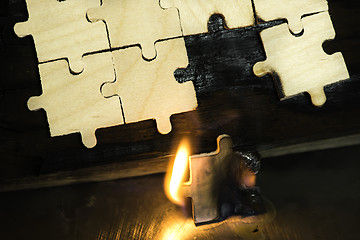 Image showing Burning wooden puzzle on dark background.