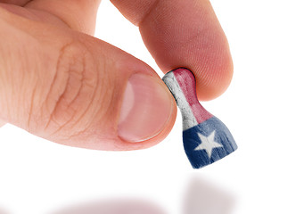 Image showing Hand holding wooden pawn, flag painting, selective focus