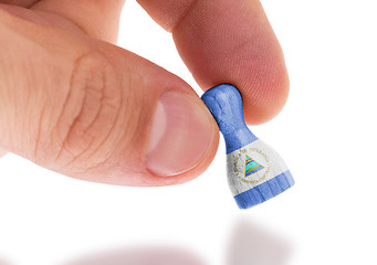 Image showing Hand holding wooden pawn, flag painting, selective focus