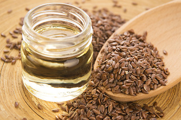 Image showing Linseed oil and flax seeds on wooden background 