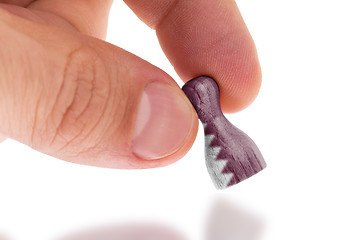 Image showing Hand holding wooden pawn, flag painting, selective focus