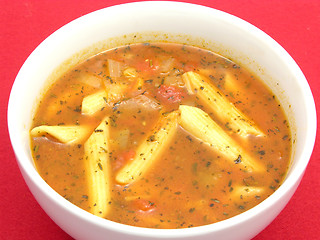 Image showing Noodle soup with tomatoes and herbs on red