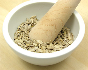 Image showing Pestling sunflower seeds in a bowl of chinaware