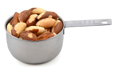 Image showing Whole brazil nuts in a metal cup measure