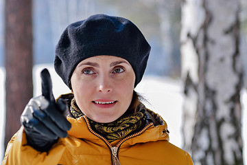 Image showing Portrait of a woman in a black beret and yellow jacket showing a finger.