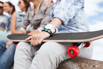 Image showing close up of female hand holding skateboard