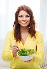 Image showing smiling young woman with green salad at home