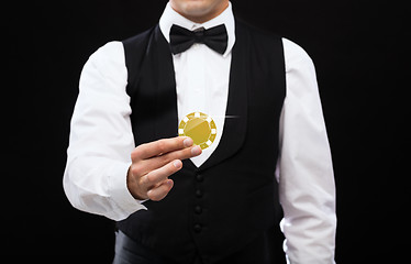 Image showing dealer holding golden poker chip