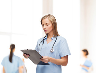 Image showing smiling female doctor or nurse with clipboard