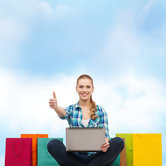 Image showing smiling girl with laptop comuter and shopping bags