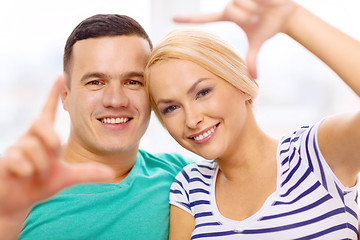 Image showing smiling happy couple making frame gesture at home