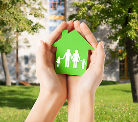 Image showing hands holding green house with family