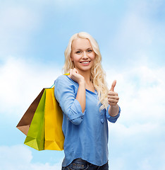 Image showing smiling woman with shopping bags showing thumbs up