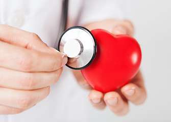 Image showing male hands holding red heart and stethoscope
