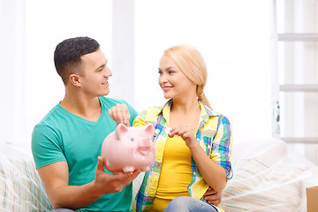 Image showing smiling couple with piggybank in new home