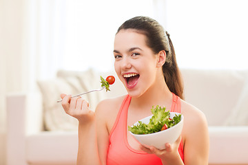 Image showing smiling teenage girl with green salad at home