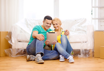 Image showing smiling couple with tablet pc in new home