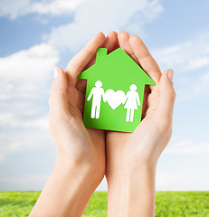 Image showing hands holding green house with family