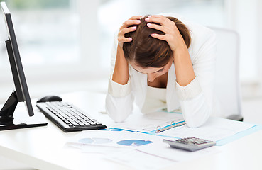 Image showing stressed woman with computer, papers, calculator