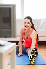 Image showing smiling teenage girl streching on floor at home