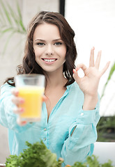 Image showing woman with glass of orange juice showing ok sign