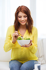 Image showing smiling young woman with green salad at home