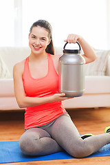 Image showing smiling teenage girl with jar of protein at home