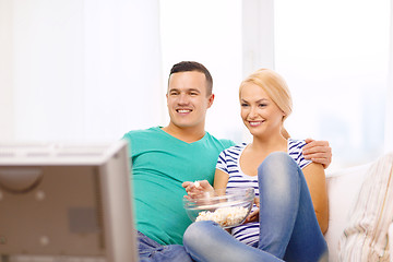 Image showing smiling couple with popcorn watching movie at home