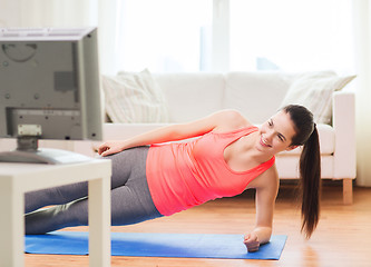 Image showing smiling teenage girl doing side plank at home