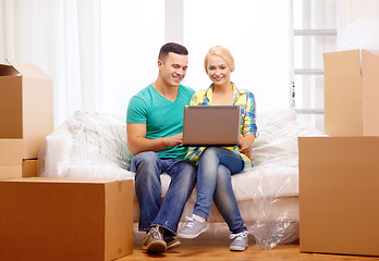 Image showing couple relaxing on sofa with laptop in new home